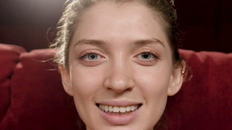 close up view of blonde woman smiling while looking at camera sitting in the cinema