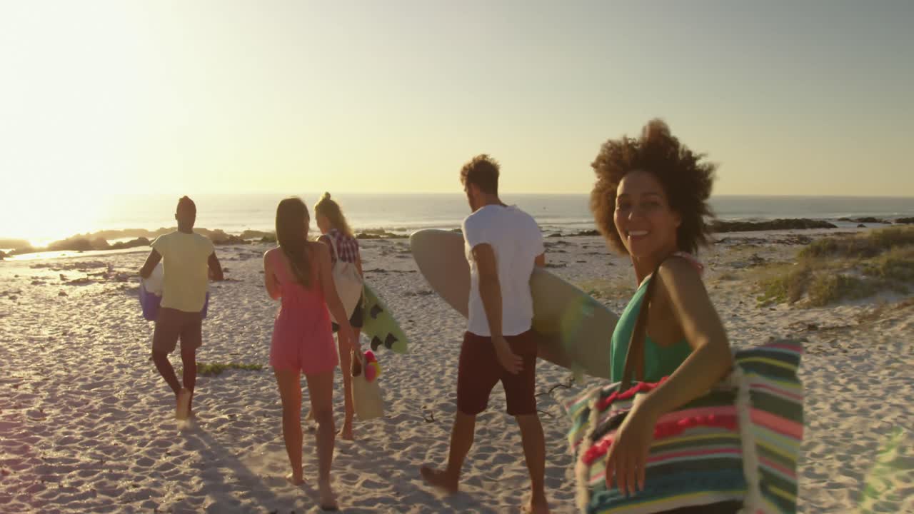 de jeunes amis adultes se promenant sur une plage au coucher du soleil 4k