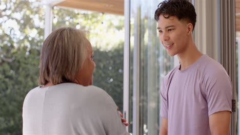 smiling young man engaging in conversation with senior woman in bright room