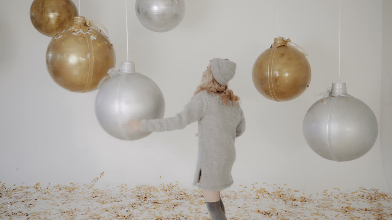 Christmas holiday party. Smiling girl throwing confetti balloons on background