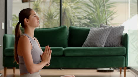 meditating at home, woman practicing yoga in living room with green sofa