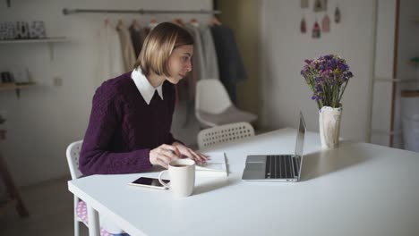 Young-woman-sitting-at-table-and-typing-on-keyboard-notebook.-Businesswoman