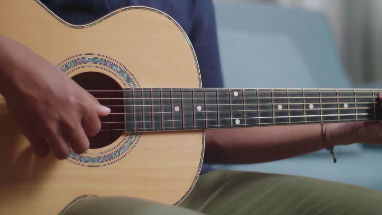 cerca de las manos del hombre tocando la guitarra en casa