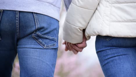 tight shot of a man and woman holding hands and walking