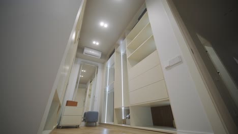 a well-organized wardrobe room displays tall, modern cabinets with ample shelving and integrated lighting, creating a sophisticated and functional clothing storage area with a comfortable chair for dressing.
