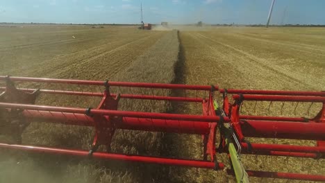 Combine-harvester-reaping-harvest-in-a-field-of-wheat-at-sunny-day-wide-angle-shot,-daylight-scene