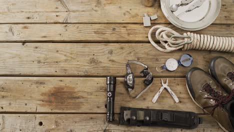 camping equipment with rope, torch, boots and copy space on wooden background