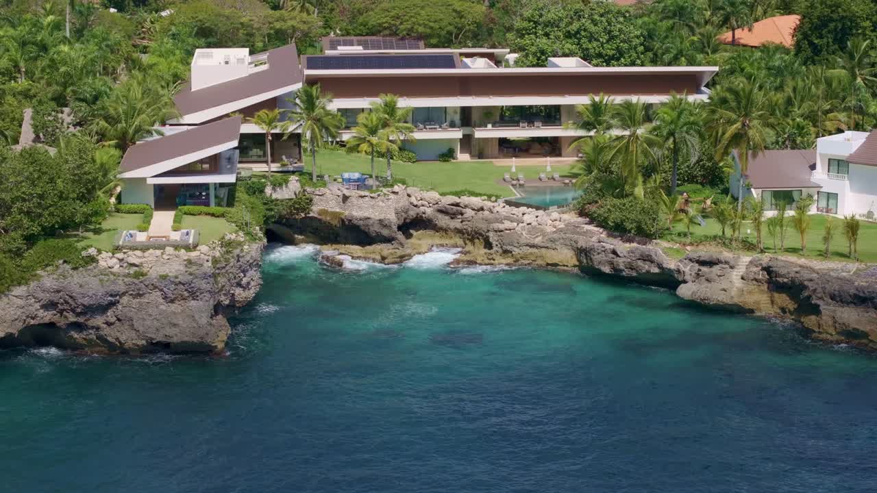 VILLAS DE LUJO at Casa de Campo, La Romana. Luxury villas mansion with private bay and palm trees. Sunny day in Dominican Republic. Aerial Orbit shot.