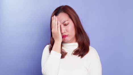 보라색 배경 위에 고립된 실망의 감정에 대처하는 좌절된 스트레스를 받은 젊은 아시아 여성