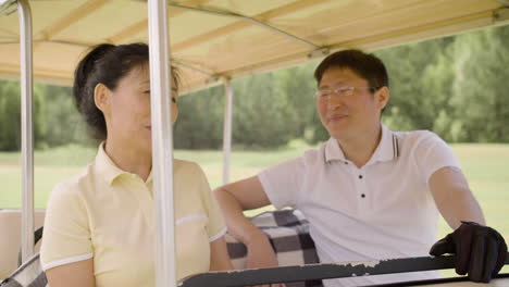 Asain-couple-having-a-good-time-on-golf-cart-on-golf-field