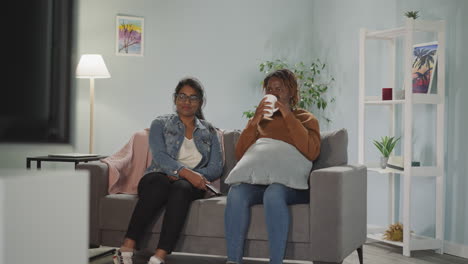 indian and african american women watch movie together