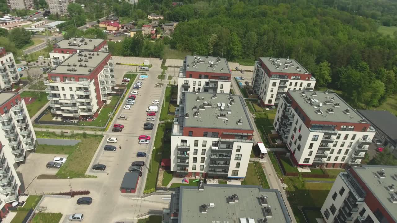 Complexe résidentiel sécurisé avec parkings et voitures, entouré d'un parc en été