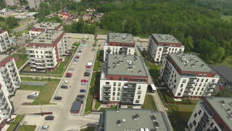 guarded residential complex with parking lots and cars, surrounded by a park in the summer