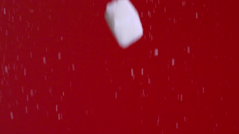 sugar cubes falling on red background