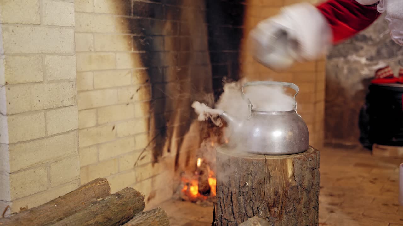Boiling retro aluminium kettle. Teapot steams. Santa Claus takes a boiling kettle. Closeup. Teapot on a log.
