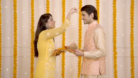 chica india poniendo tilak en la frente de su marido