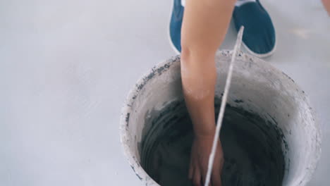 woman in denim shoes wets rag with water on floor close view