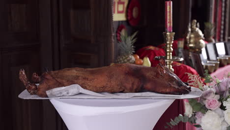 roast pig centerpiece on a white tablecloth at a formal banquet, with decorative background elements including flowers, fruits, and candles