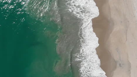 slow aerial drone footage above tropical ocean shore with breaking waves