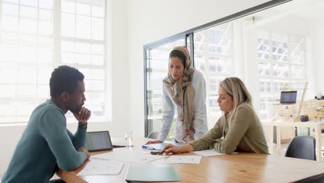 busy diverse business people discussing work at table with tablet in slow motion