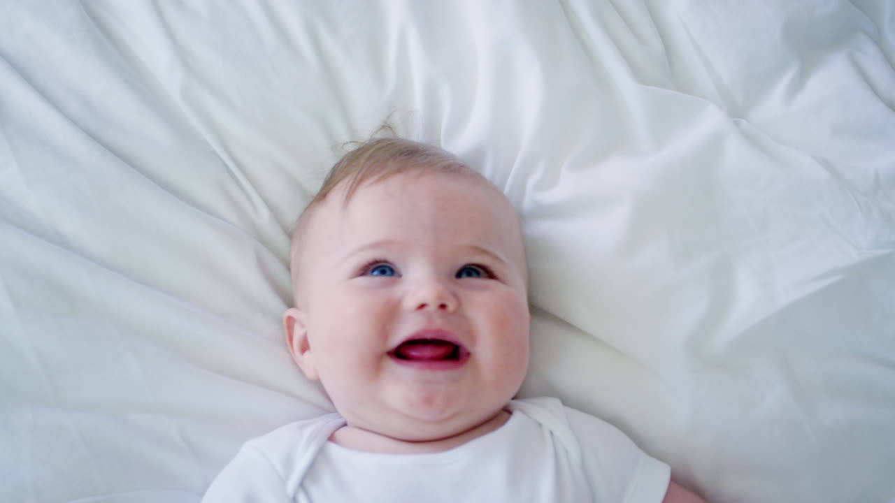 fotografía aérea de un bebé acostado en la cama y riendo