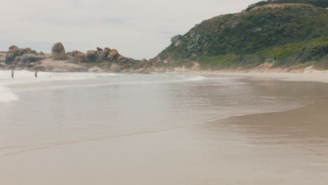 Lustiger-Afroamerikanischer-Mann,-Der-Mit-Flossen-Am-Strand-Im-Meerwasser-Spaziert-Und-Sich-Zum-Schwimmen-Bereit-Macht,-Um-Den-Sommer-Am-Meer-Zu-Genießen,-4k