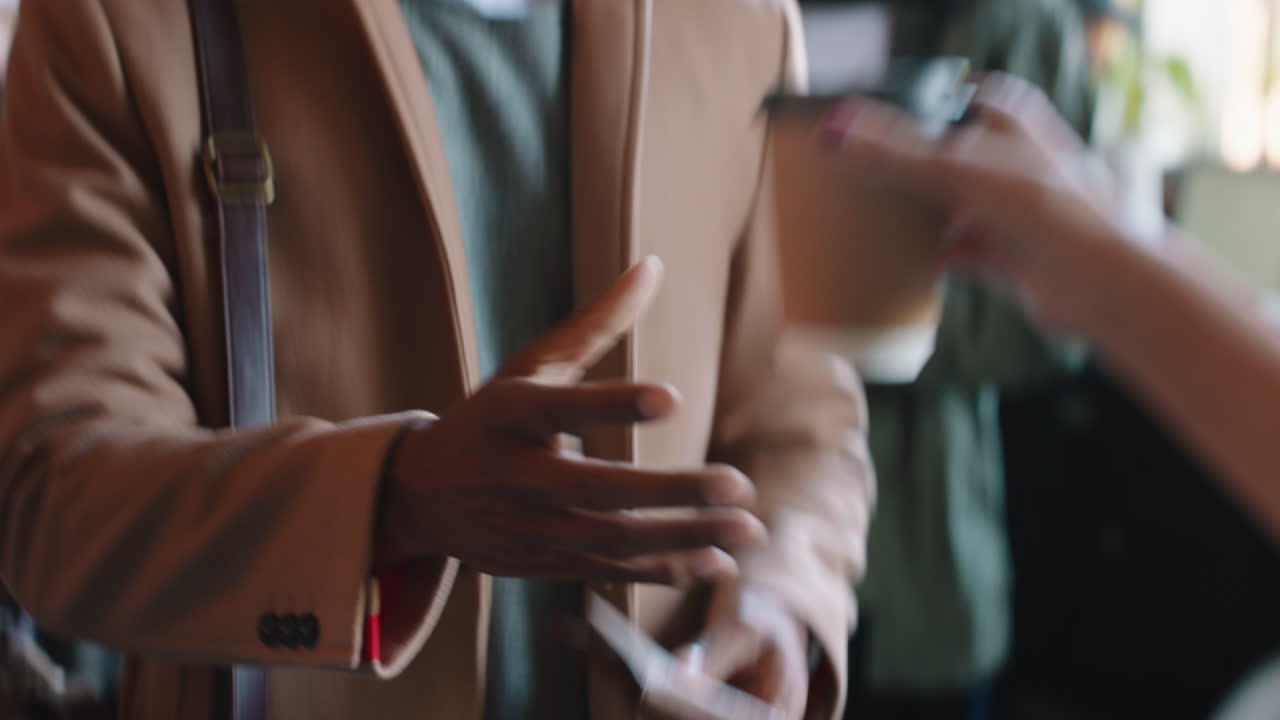 매력적인 젊은 남자가 신용 카드 거래 서비스를 사용하여 지불하고 카페에서 커피를 구입하고 레스토랑에서 돈을 쓰고 있습니다.