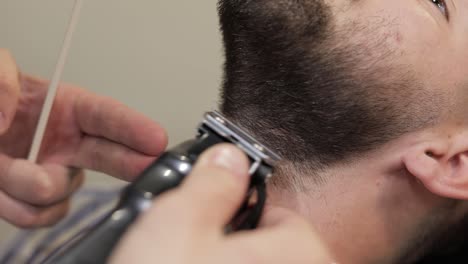 client with black beard during beard shaving in barber shop. groom, masculine