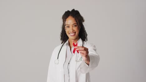 Video-of-smiling-biracial-female-doctor-holding-orange-kidney-cancer-ribbon