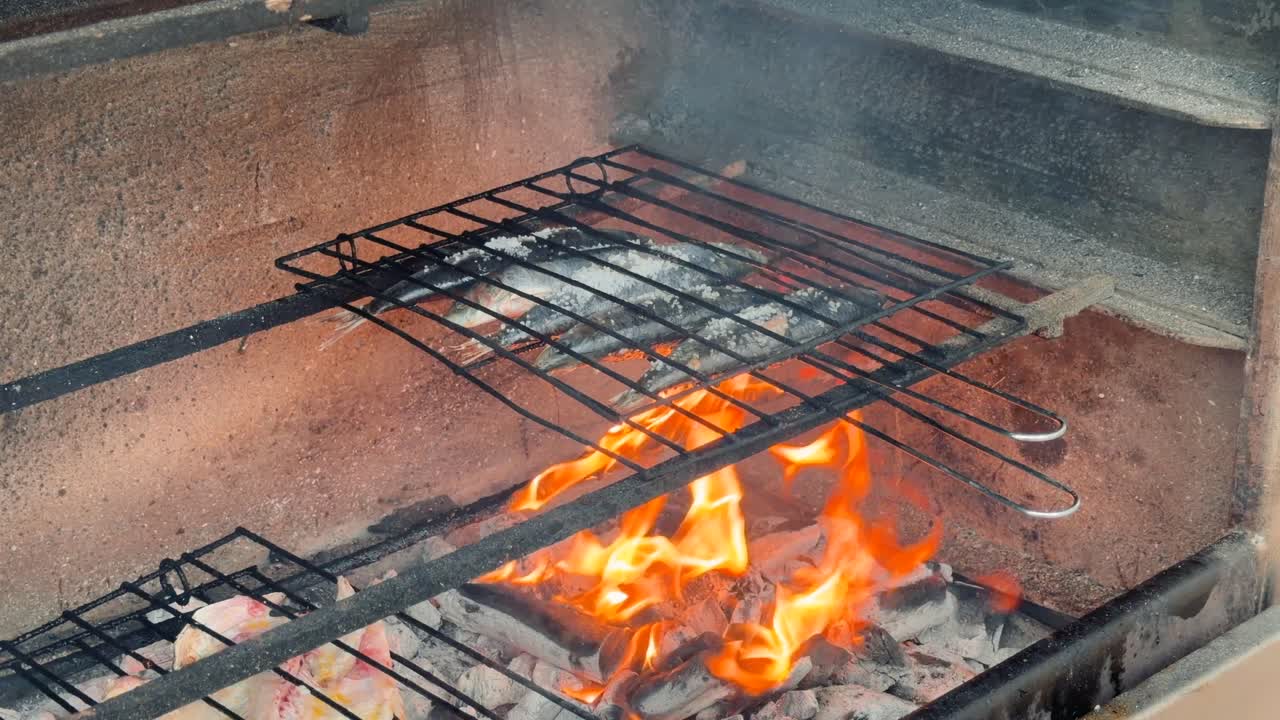 Pesce e carne che grigliano su fuoco aperto sul barbecue