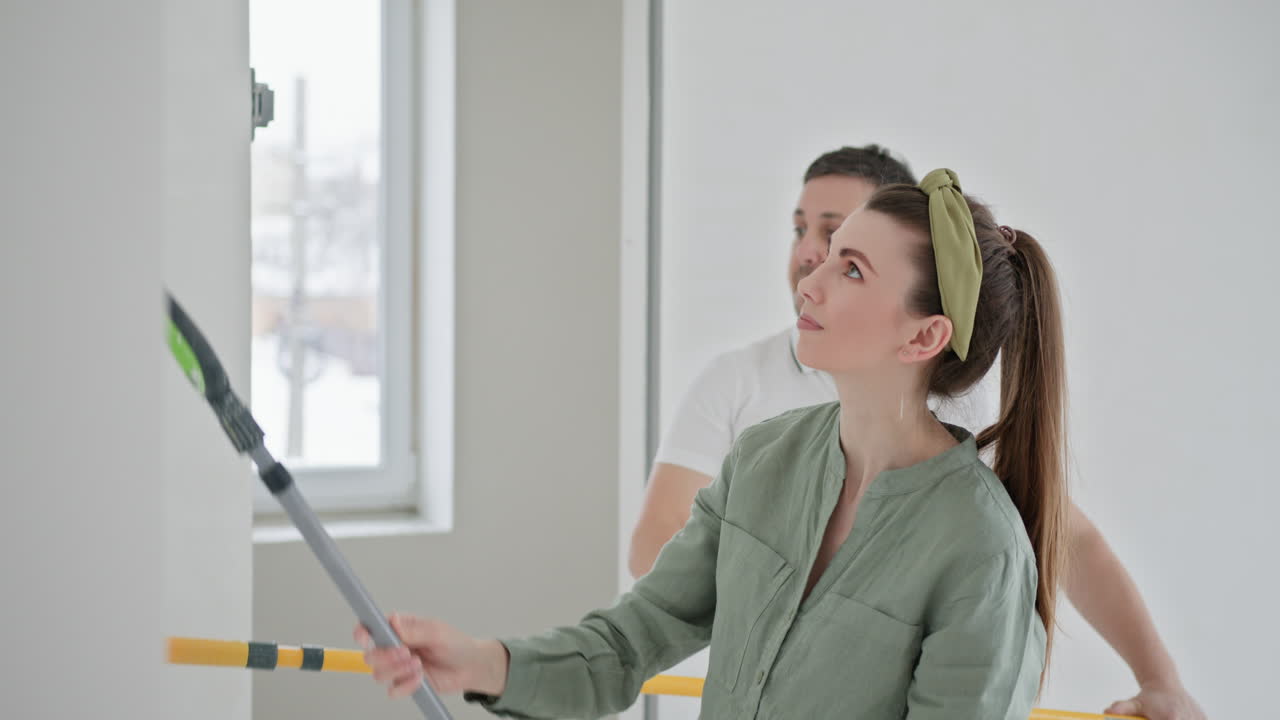 pareja pintando una pared en un nuevo hogar