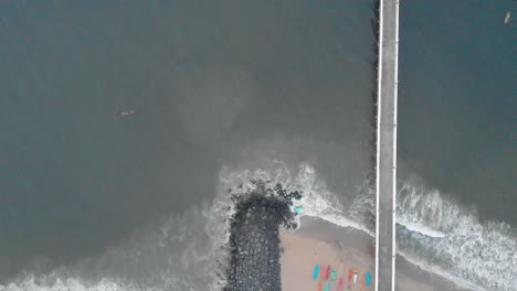 4k aerial crane moving down shot of a shipping port pier on a sunrise with monsoon clouds covered near rock beach shot with a drone, pondicherry, india