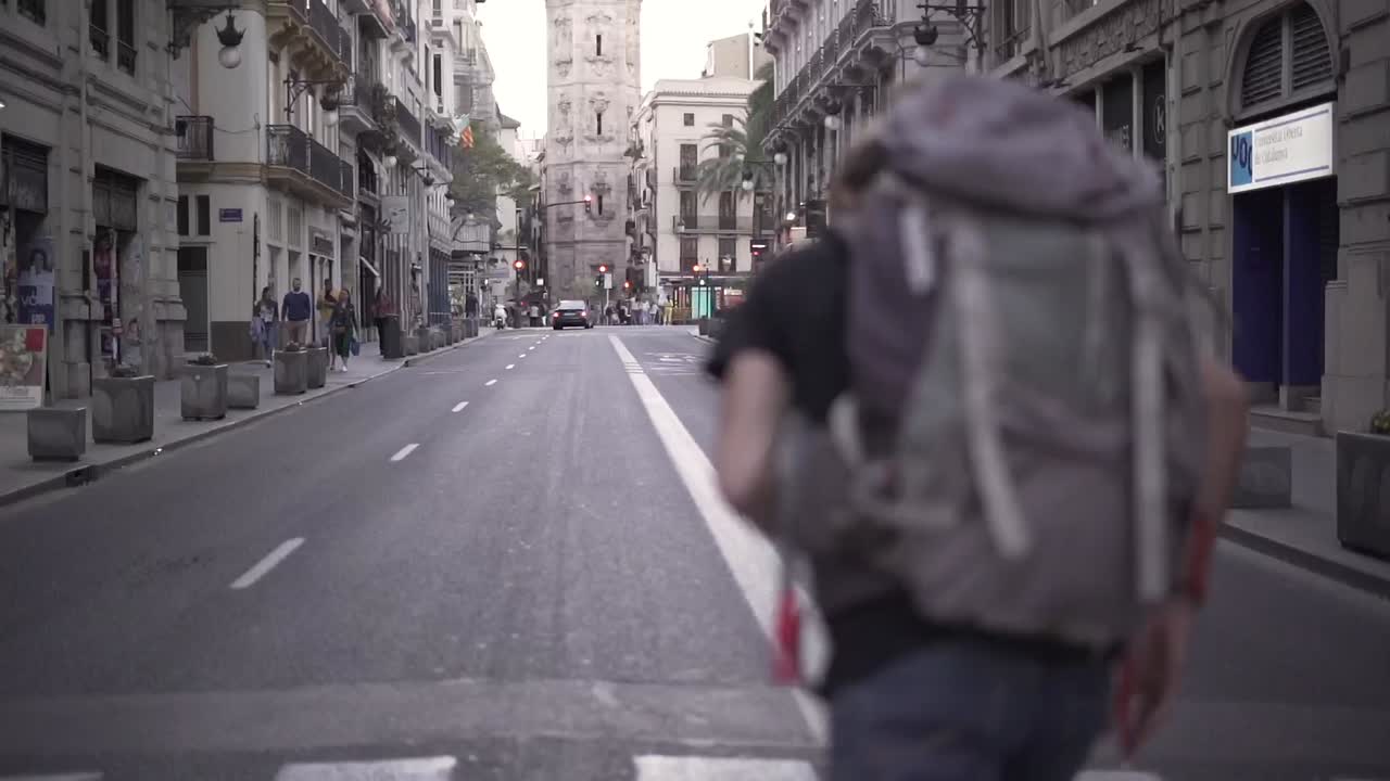 Man with a Backpack Walking Down a City Street