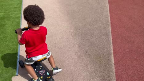 two year old african european child funny riding his first skateboard