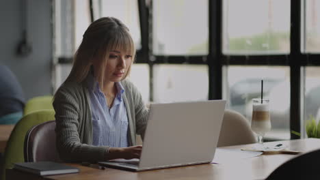 joven trabajadora de oficina asiática atractiva sentada en la computadora portátil en el escritorio trabajando y pensando. mujer de raza mixta trabajando desde casa en la computadora portátil.
