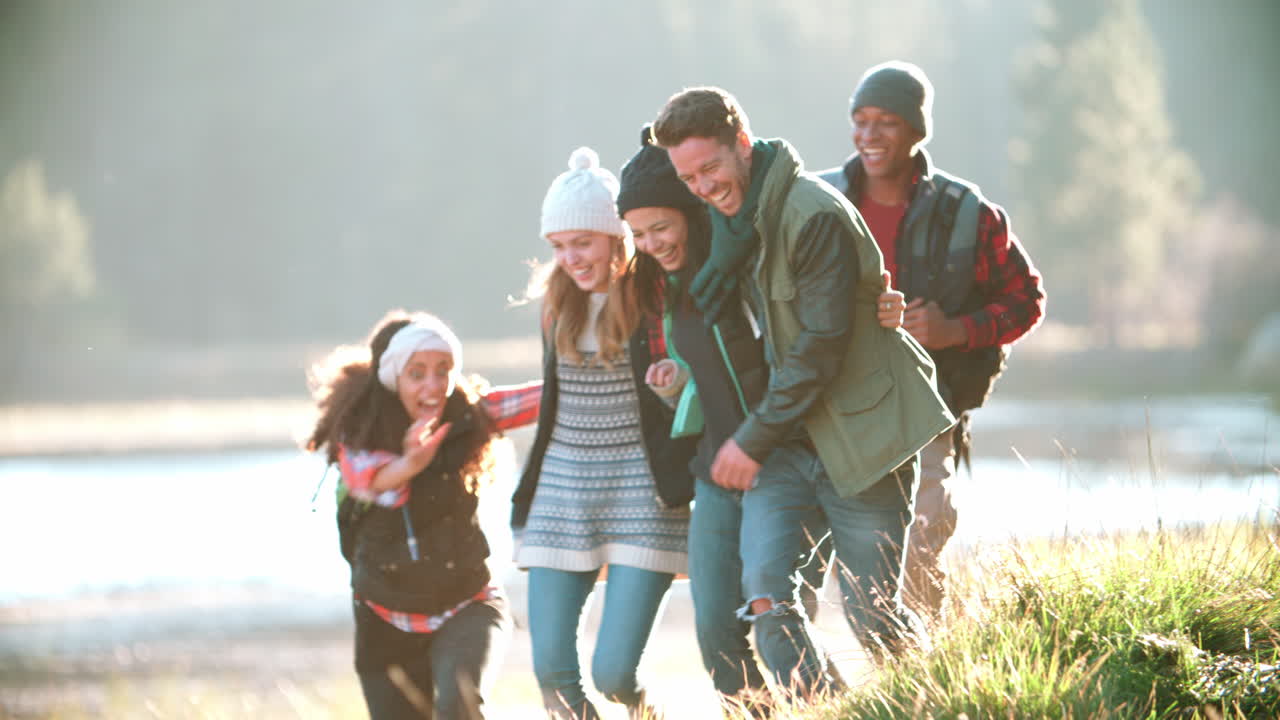 캠핑 여행 중인 다섯 명의 친구들이 호수 근처에서 달리고, 느린 속도로