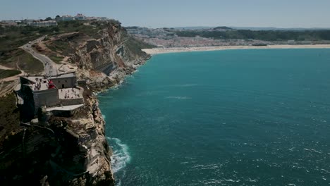 drone shot of nazaré lighthouse heading to the beach