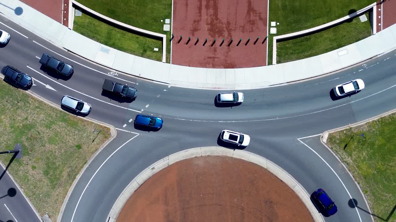 Drone aerial landscape of car vehicles and traffic driving around roundabout turn at intersection corner in lanes Canberra ACT Australia transport travel infrastructure pathway tourism