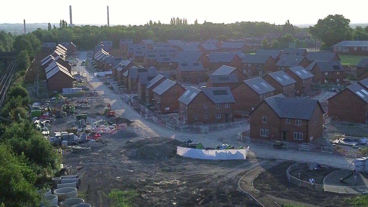 Unfinished new home framework construction site aerial view circling development estate rooftops