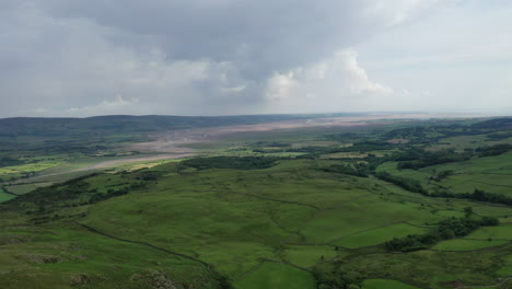 Aerial-view-of-rural-fields-and-a-costal-bay-at-low-tide,-on-a-bright-but-cloudy-day