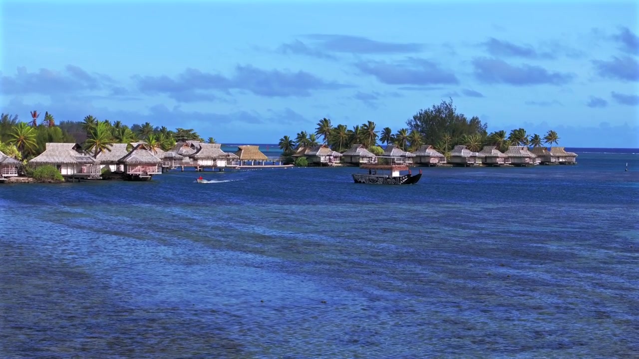 Bungalow-rakennuksia Cookinlahden koralliriuttakanavan yllä, purjeveneitä ja jahteja Opunohunlahdella, Bora Boralla, Moorealla, Ranskan Polynesiassa. Ilmakuva dronella Tahitin saaren Ta'ahiamanun yleiseltä rannalta aamulla, aurinkoisen sinisen taivaan alla.