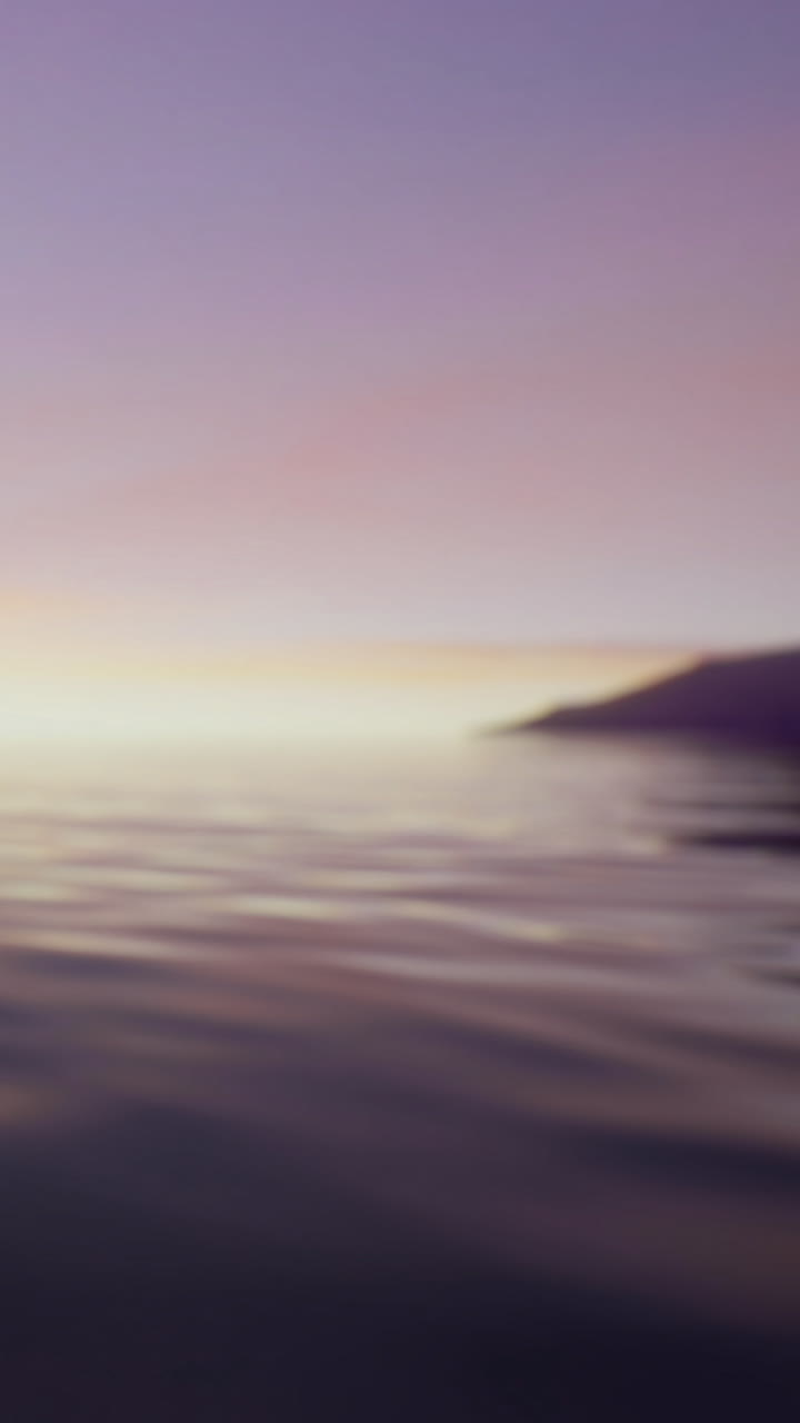 Sunset view over water near mountains and distant shoreline in calm evening