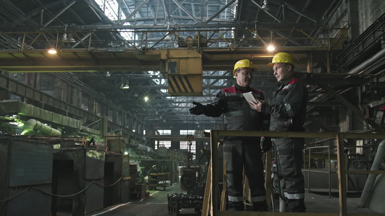 Plant Workers In Hard Hats Talking At Workplace