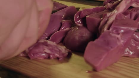 Raw-pig-heart-placed-on-cutting-board-and-sliced-using-knife,-closeup