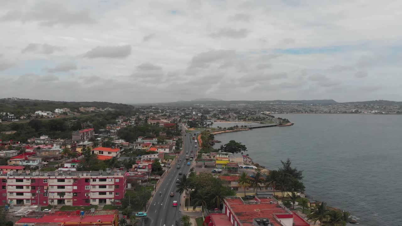 4k drone footage of a highway in Cuba with old cars driving down the road, looking out to the distance with the ocean beside.