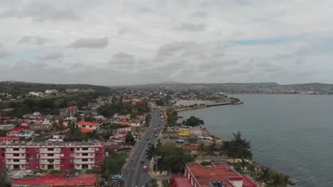 4k drone footage of a highway in cuba with old cars driving down the road, looking out to the distance with the ocean beside.