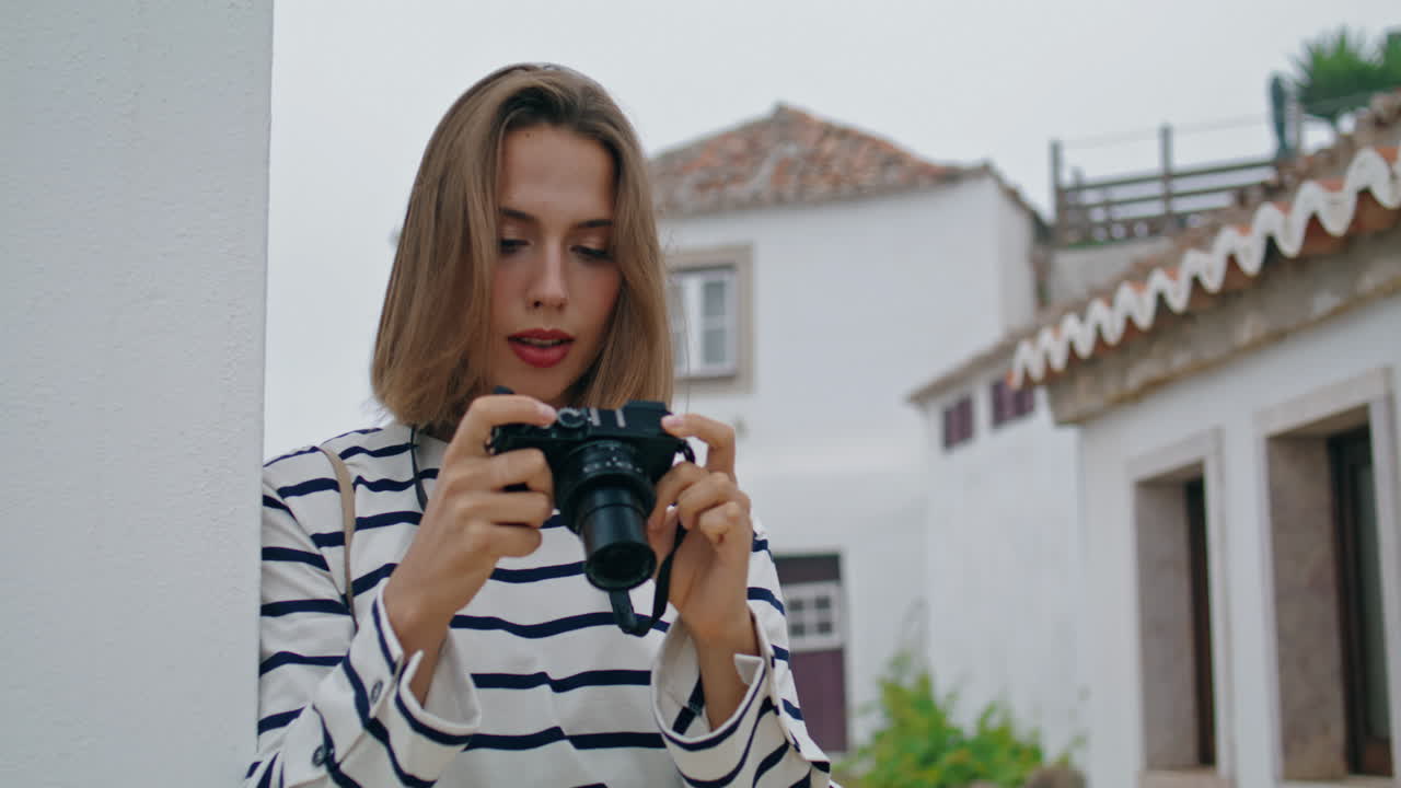 색으로 된 집에서 오래된 카메라 사진을 찍는 소녀. 아름다운 관광 여행