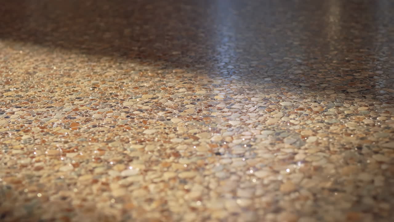 Close-up of a polished terrazzo or pebble textured floor with reflections