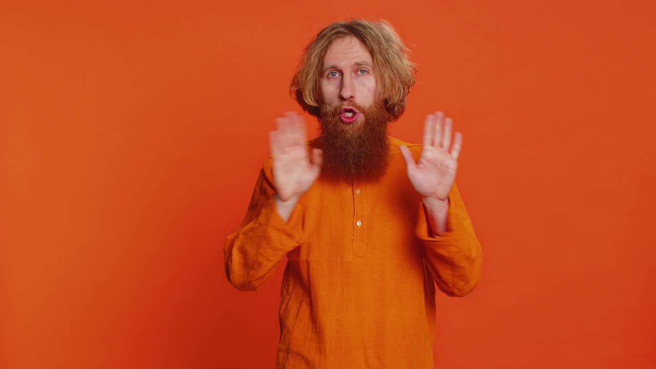 Frightened young man closing mouth with hands refusing to tell terrible secret unbelievable truth