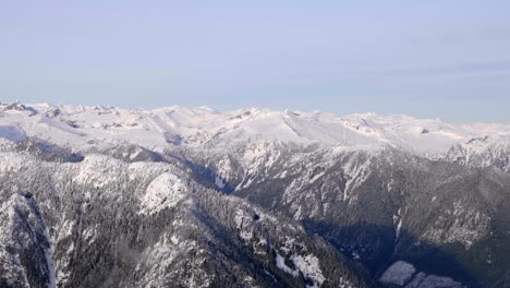 snowy high mountains along the calm river near squamish at whistler area in british columbia, canada